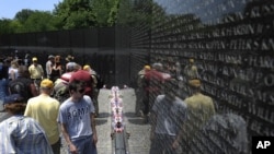 Visitors to the Vietnam Veterans Memorial look at the tens of thousands of names carved into the wall.