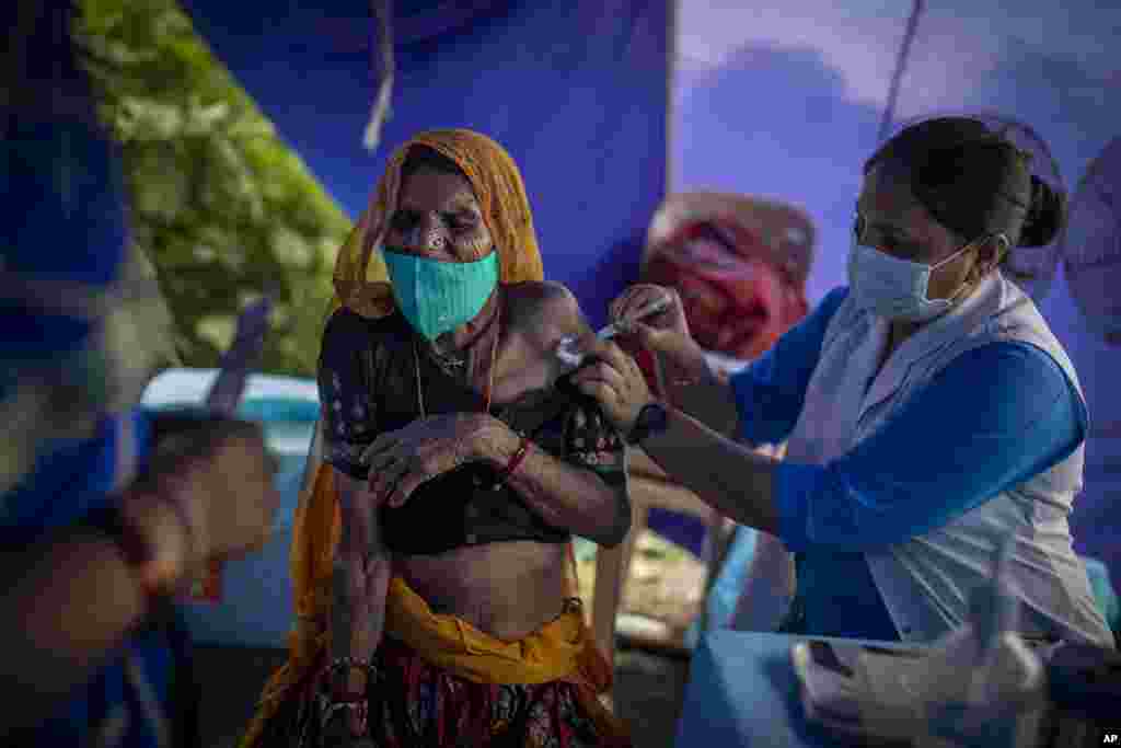 An elderly woman reacts as a health worker inoculates her during a special vaccination drive for homeless and migrant workers against COVID-19 in New Delhi, India.