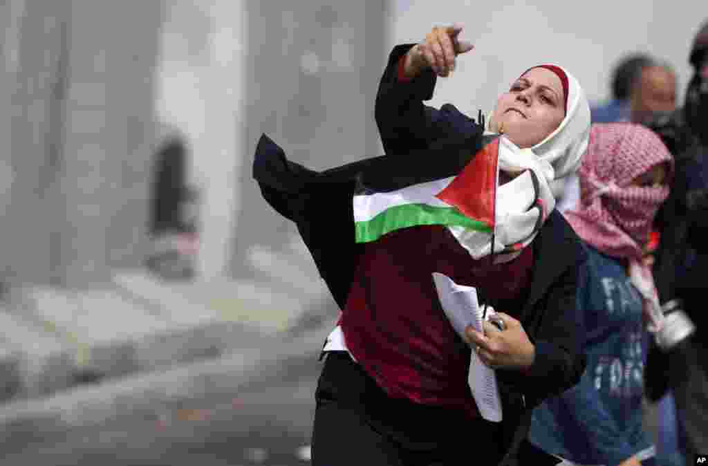 Một phụ nữ Palestine ném đá vào những binh sĩ Israel tại trạm kiểm soát Qalandia giữa Jerusalem và thành phố Ramallah, vùng Bờ Tây. Phụ nữ Palestine kỷ niệm Ngày Phụ nữ Quốc tế bằng cách tuần hành đến trạm kiểm soát và xung đột với binh sĩ Israel.