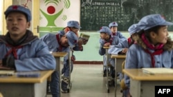 Children dressed in uniform gather in their classroom at the Beichuan Red army elementary school in Beichuan, southwest China's Sichuan province, To go with AFP story China-politics-education-history, Jan. 21, 2015.