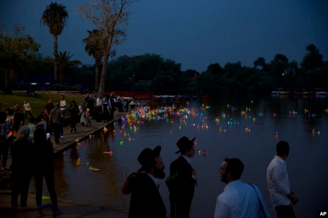 People look upon floating handmade boats with the names of Nazi concentration camps, during a ceremony marking the annual Holocaust Remembrance Day in Hayarkon park in Tel Aviv, Israel, May 1, 2019.