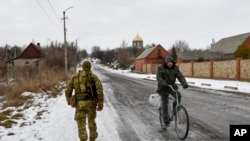 FILE - A Ukrainian serviceman patrols a street near the frontline with Russia-backed separatists in Verkhnotoretske village in Yasynuvata district, Donetsk region, eastern Ukraine, Jan. 22, 2022.