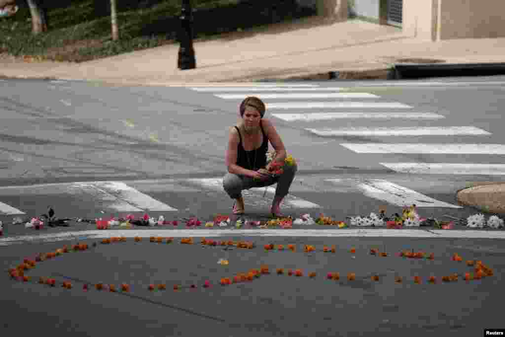 A woman kneels at a makeshift memorial for the victims of a car that plowed into counter-protesters after a &quot;Unite the Right&quot; rally organized by white nationalists in Charlottesville, Aug. 13, 2017.