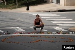 FILE - A woman kneels at a makeshift memorial for the victims of a car that plowed into counter-protesters after a "Unite the Right" rally organized by white nationalists in Charlottesville, Va., Aug. 13, 2017.