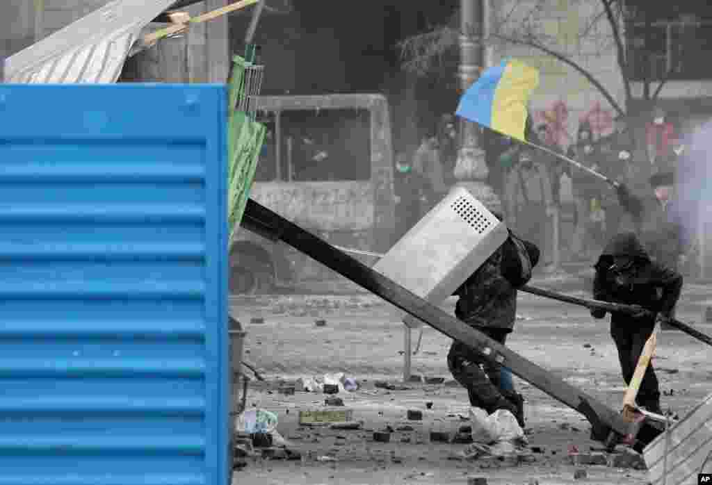 Protesters shield themselves as they clash with police in central Kyiv, Jan. 20, 2014.