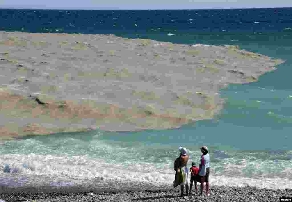 Tourist on the beach look at the sea after local authorities forbid swimming during a water safety test following a heavy storm in Nice, France. 