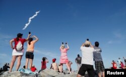 Spectators at Cocoa Beach watch SpaceX's first Falcon Heavy rocket launch from the Kennedy Space Center, Florida, Feb. 6, 2018.