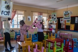 Teachers unstack classroom furniture in anticipation of attendance on day one of re-opening schools in Kampala, Jan. 10, 2022.