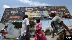 Quelques personnes marchent devant une pancarte publicitaire géante du Marché des Arts du Spectacle Africain d'Abidjan (Masa), à Abidjan, le 9 mars 2018.