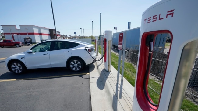 A Tesla charges at a station in Topeka, Kan., Monday, April 5, 2021. The president and the auto industry maintain the nation is on the cusp of a gigantic shift to electric vehicles and away from liquid-fueled cars, but biofuels producers and some of their