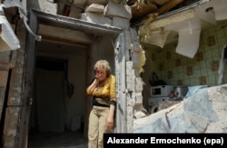 FILE - A local woman reacts next to her destroyed home after shelling in pro-Russian rebels-controlled Staromykhaylivka village near of Donetsk, Ukraine, May 24, 2016.