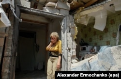 FILE - A local woman reacts next to her destroyed home after shelling in pro-Russian rebels controlled Staromykhaylivka village near of Donetsk, Ukraine.