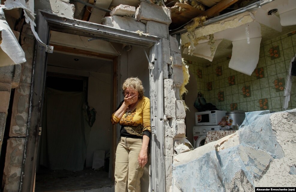A local woman reacts next to her destroyed home after shelling in pro-Russian rebel-controlled Staromykhaylivka village near of Donetsk, Ukraine, 24 May 2016.