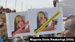 A protester holds up signs protesting against UNMISS head Hilde Johnson at a rally in Juba after South Sudanese government forces found weapons in a UN overland shipment.