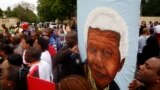 A group of mourners carrying a picture of South African leader Nelson Mandela, sing and dance outside his Johannesburg home, Dec. 6, 2013, after the freedom fighter passed away Thursday night after a long illness.
