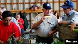 El secretario de Agricultura de EE.UU., Sonny Perdue (centro), visita una granja productora de maíz en Valatie, Nueva York, el 23 de agosto de 2018. Perdue dice que el presidente Donald Trump anunciará pronto un plan para aumentar la demanda de biocombustibles.