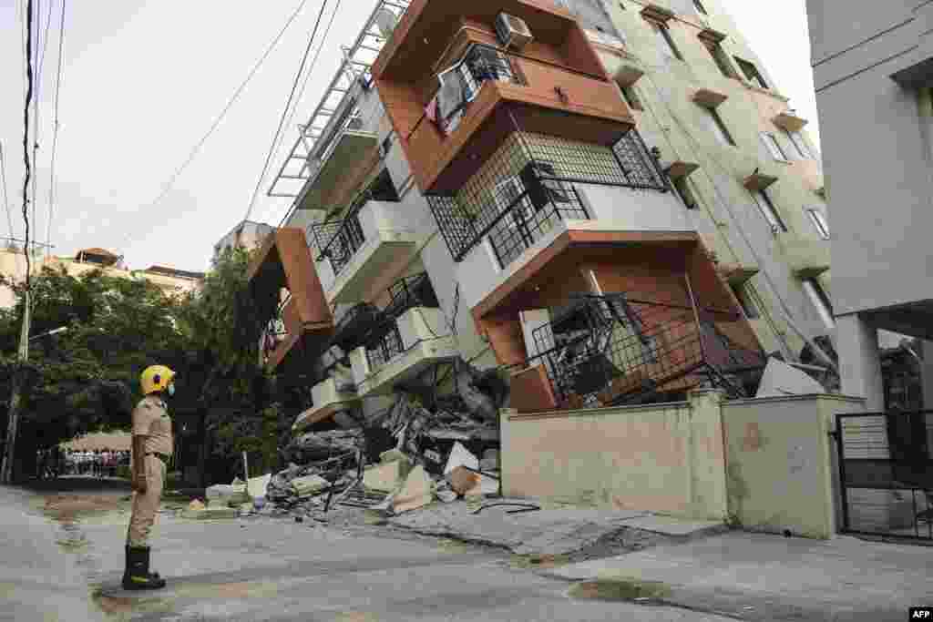 Seorang petugas pemadam kebakaran menyaksikan gedung apartemen bertingkat yang ambruk di Bangalore, India hari Kamis (7/10), namun tak ada laporan korban jiwa (Foto: AFP).&nbsp;
