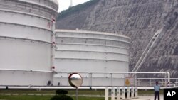 FILE - a security guard stands guard near oil tanks at Zhoushan Oil Reserve in Zhoushan in Zhejiang Province, China, June 30, 2009. Cooling economies in Asia and Europe also have weakened demand, sending the price below $50 for the first time since April.