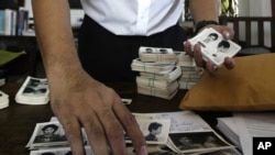 In this photo taken on Aug. 20, 2012, Director of Documentation Center of Cambodia, Chhang Youk arranges photos, a part of about a thousand of newly-discovered photo collection of detainees at the former Khmer Rouge main prison S-21, in his office in Phno