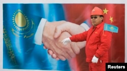 FILE - A Chinese worker stands in front of a poster during the inauguration ceremony of the Kazakh stretch of the 1,833-kilometer (1,139-mile) Turkmenistan-China pipeline, Dec. 12, 2009.