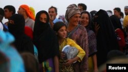 Iraqi refugees, who fled from the violence in Mosul, line up to receive food.