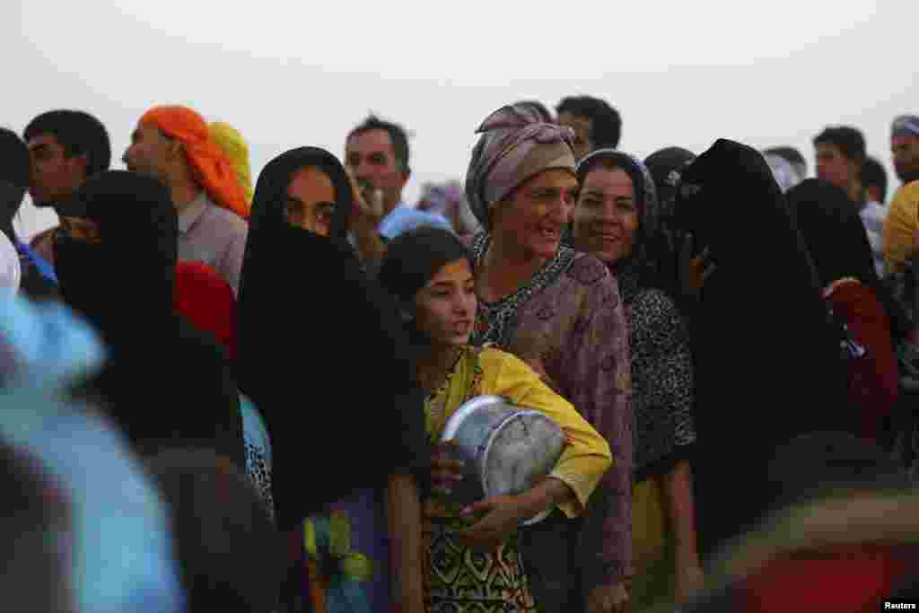 Iraqi refugees who fled from the violence in Mosul line up to receive free food during the holy fasting month of Ramadan, inside the Khazer refugee camp on the outskirts of Irbil, in Iraq&#39;s Kurdistan region, June 29, 2014. 