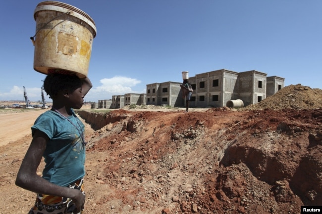 FILE - A woman walks past a Chinese construction site in Lubango, Angola, March 5, 2014.
