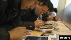 Customers test out Apple iPads in an Apple Store in downtown Shanghai, February 29, 2012.