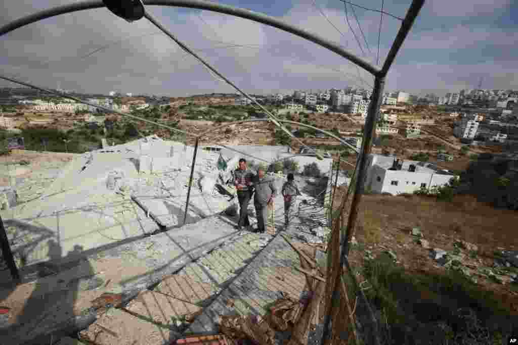 Palestinians inspect the remains of the home of Hussam Kawasma in the West Bank, city of Hebron, Aug. 18, 2014.