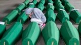 A girl inspects coffins prepared for burial, in Potocari near Srebrenica, Bosnia. The remains of 33 victims of Srebrenica massacre will be buried on July 11, 2019, 24 years after Serb troops overran the eastern Bosnian Muslim enclave of Srebrenica and executed some 8,000 Muslim men and boys.