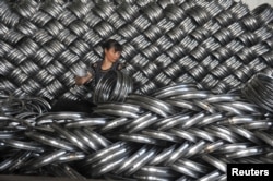 FILE - A woman works on packaging bicycle rim steels for export at a workshop of a company manufacturing sports equipments in Hangzhou, Zhejiang province, China, June 4, 2018.