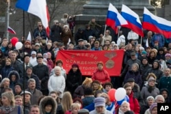 People with Russian and Crimean flags await a concert where Russian President Vladimir Putin later made an appearance in Sevastopol, Crimea, March 14, 2018.