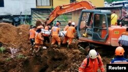Trabajadores de Defensa Civil colombiana desentierran el cuerpo de una persona fallecida en un deslizamiento de tierra causado por las fuertes lluvias en el país, en Mallana, Colombia 2 de noviembre de 2021.