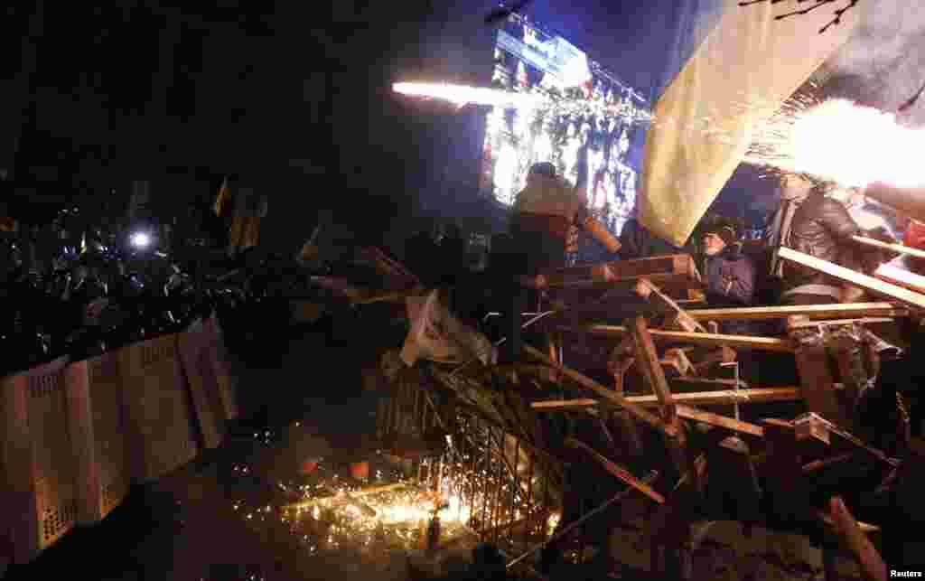 Pro-European integration protesters standing behind barricades confront a line of riot police approaching at Independence Square in Kyiv, Dec. 11, 2013.
