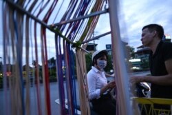 Seorang perempuan (kiri) membeli kabel pengisi daya ponsel dari pedagang kaki lima saat matahari terbenam di Hanoi, 9 Juli 2020. (Foto: Manan VATSYAYANA / AFP)