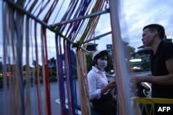Seorang perempuan (kiri) membeli kabel pengisi daya ponsel dari pedagang kaki lima saat matahari terbenam di Hanoi, 9 Juli 2020. (Foto: Manan VATSYAYANA / AFP)
