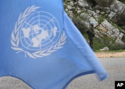 FILE - A United Nations flag waves as Spanish U.N. peacekeepers carry out a foot patrol in the disputed Chebaa Farms area between Lebanon and Israel, in southeast Lebanon, Feb. 24, 2015.