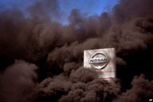 Asap hitam mengepul akibat ban yang dibakar oleh para pengunjuk rasa yang memprotes penutupan pabrik Nissan di Barcelona, Spanyol, 28 Mei 2020.