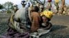 FILE - A Rwandan woman collapses with her baby on her back alongside the road connecting Kibumba refugee camp and Goma, July 28, 1994. 