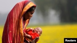 FILE - A woman holds her 22-day-old grandson as she walks on the outskirts of Dhaka, Bangladesh, Jan. 22, 2014. 