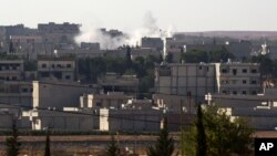 A mortar shelling lands in the residential area in Kobani in Syria, as seen from Mursitpinar near Suruc, Turkey, as fighting intensified between Syrian Kurds and the militants of Islamic State, Oct. 5, 2014.