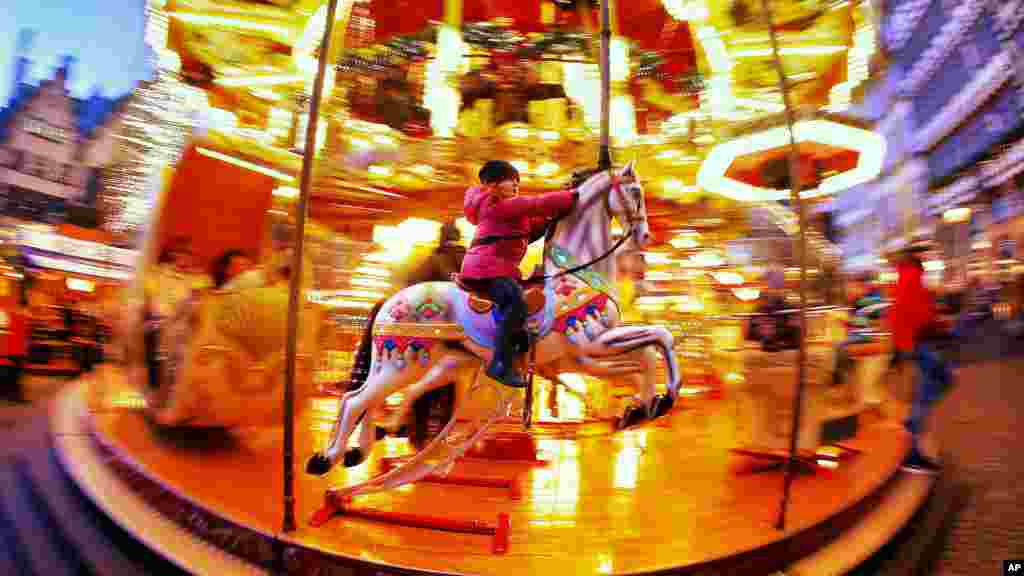 A little girl rides a horse on a merry-go-round on the Christmas market in Frankfurt, Germany.