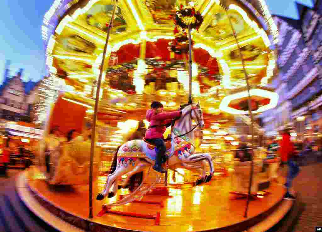 A little girl rides a horse on a merry-go-round on the Christmas market in Frankfurt.