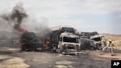 Afghan firefighters spray water on burning NATO supply trucks in Samangan, north of Kabul, Afghanistan, July 18, 2012. 