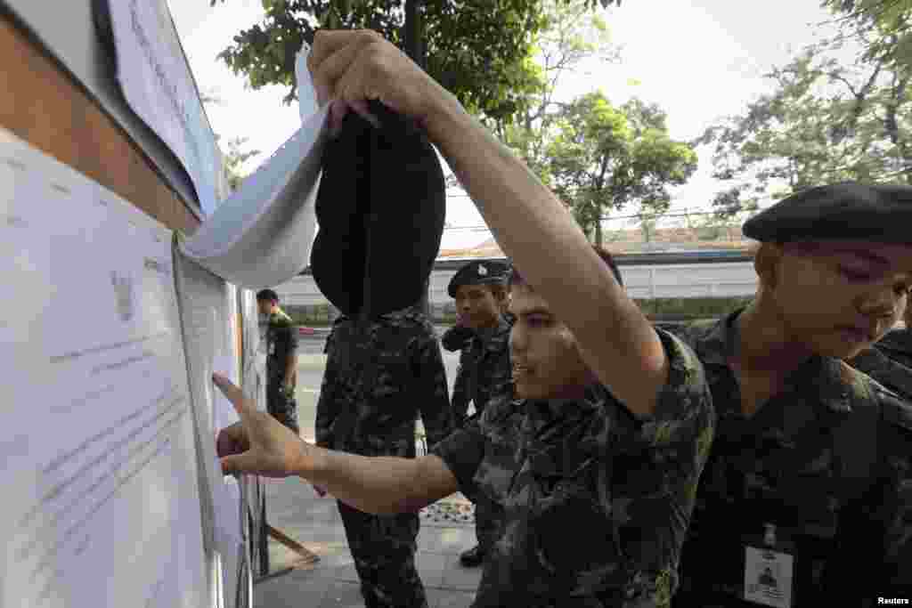 Soldiers check electoral lists as they prepare to vote at a polling station in Bangkok, March 30, 2014.