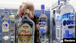 지난 2014년 러시아 상테부르크에서 열린 농공산업 전시회에서 한 직원이 보드카를 전시하고 있다. 러시아에서는 비싼 술 대신 술 성분이 있는 화장수나 향수를 마시는 사람이 많은 것으로 알려져 있다. (자료사진)