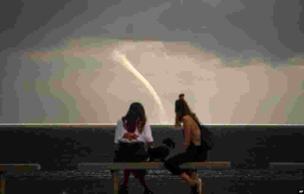 People look at a funnel cloud formed near a beach in Barcelona, Spain.
