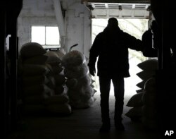 FILE - Richard McNulty of Sankey's Feed Mill walks through stacks of feed available at the store in Volant, Pa., April 5, 2018. McNulty said ground soybean is mixed in with certain livestock feeds. Many small U.S. manufacturers are feeling the impact of tariffs of up to 25 percent that the Trump administration has imposed on thousands of products imported from China, Europe, Mexico, Canada, India and Russia, and of retaliatory tariffs that countries have put on U.S. exports.