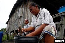 A villager cleans a sea cucumber outside her house in Mapan Mapan, Sabah, Malaysia, July 7, 2018.