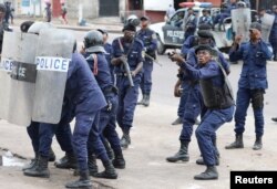 FILE - Policemen react after a protester threw a stone from Notre Dame Cathedral compound in Kinshasa, Democratic Republic of Congo, Feb. 25, 2018.